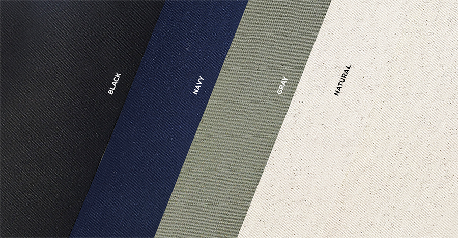 Four colors of organic cotton canvas fabric including black, navy, gray and natural. The fabric swatches are laid one on top of the other at an angle.