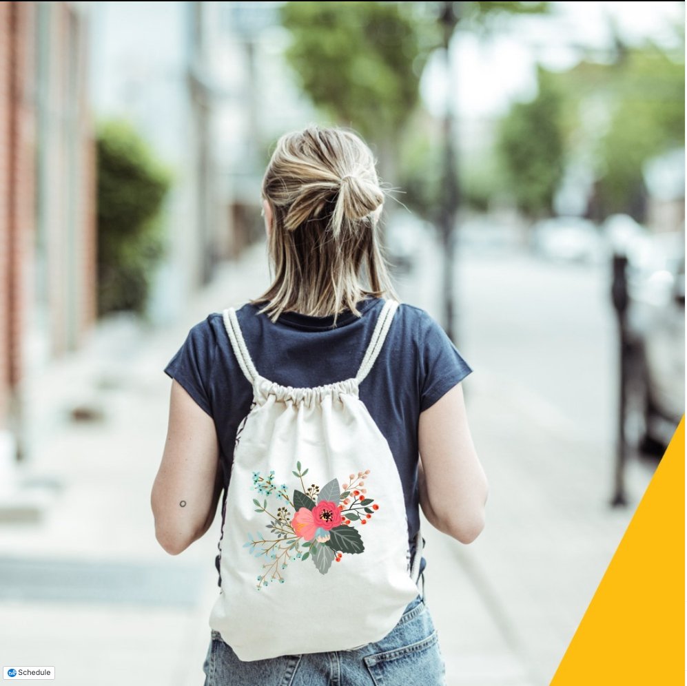 A woman wearing a natural colored cotton canvas backpack with rope drawstrings facing away from the camera. The bag a has a floral print in the center. 