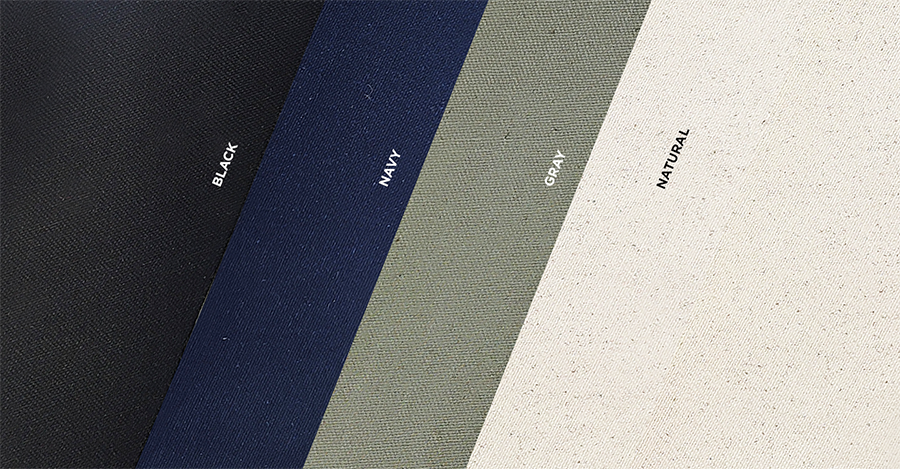 Four colors of organic cotton canvas fabric including black, navy, gray and natural. The fabric swatches are laid one on top of the other at an angle. 