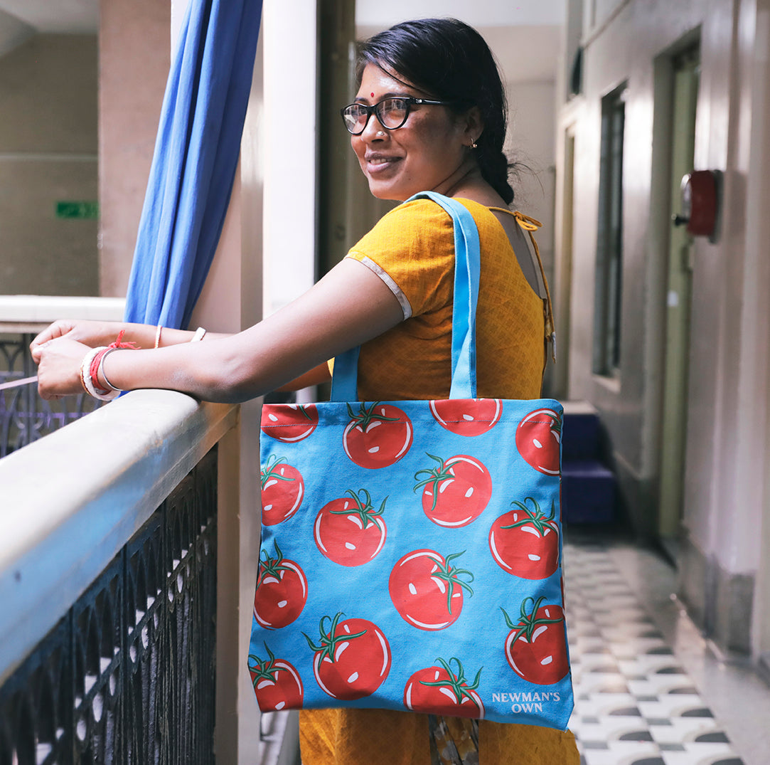 Joyya Staff woman holds a handmade tote bag with tomatoes on it made for Newmans Own Salsa