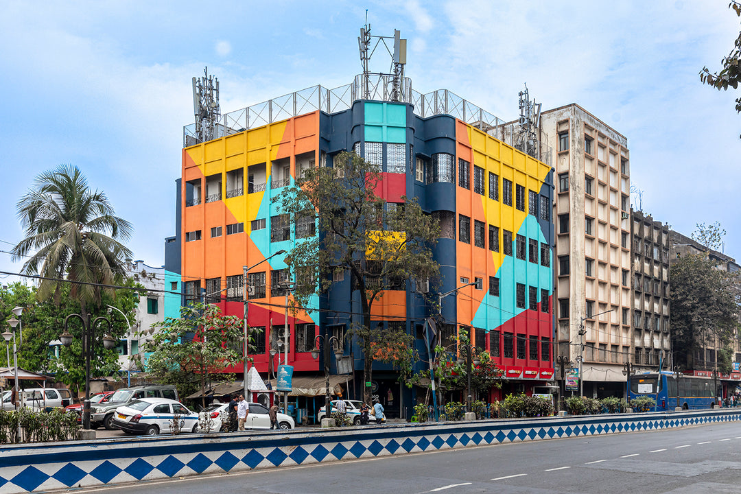 A building with a brightly painted geometric pattern covering all sides of it. It is painted in blue, yellow, orange, teal and red. 