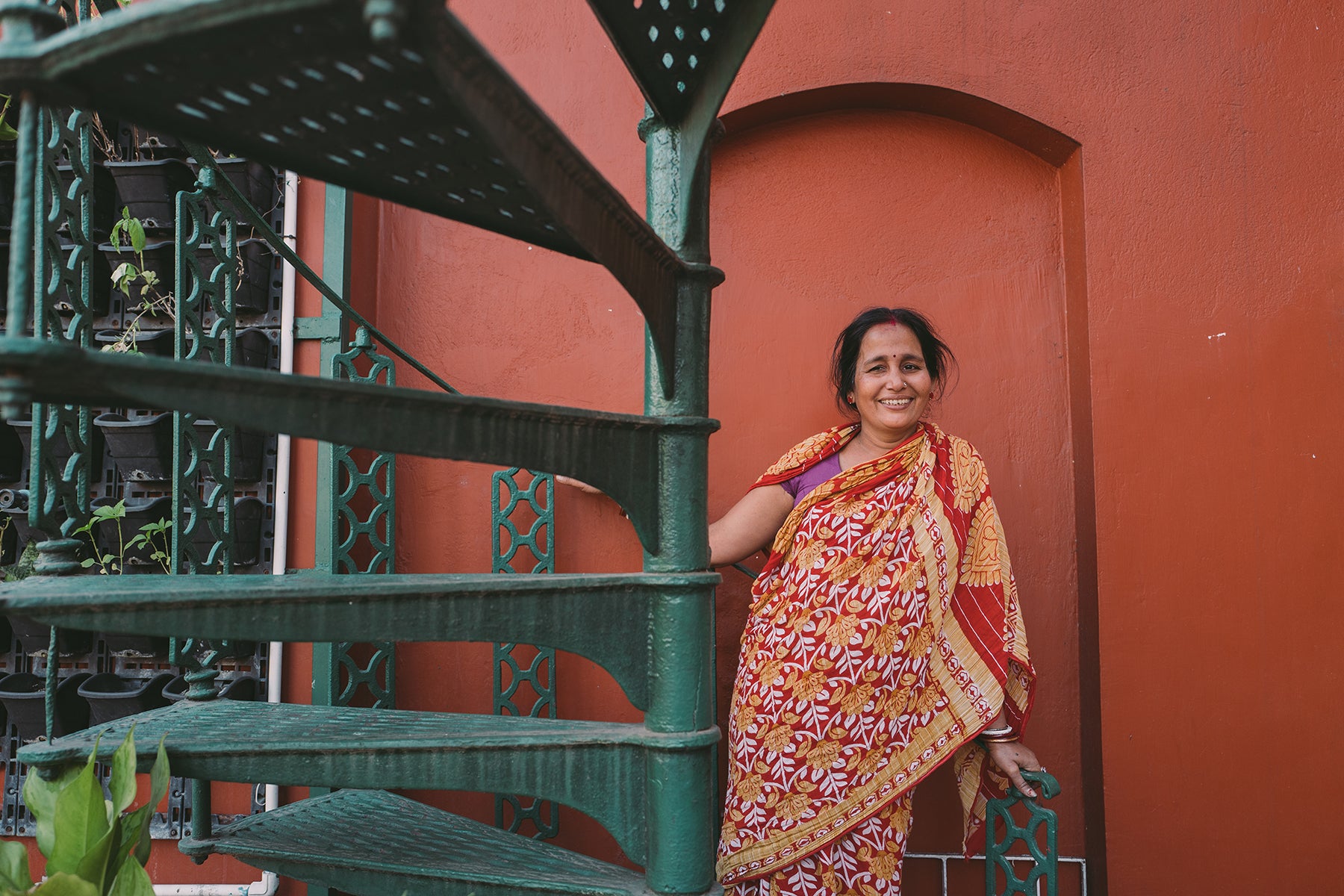 Joyya staff woman standing at the foot of a spiral stair case in Kolkata India