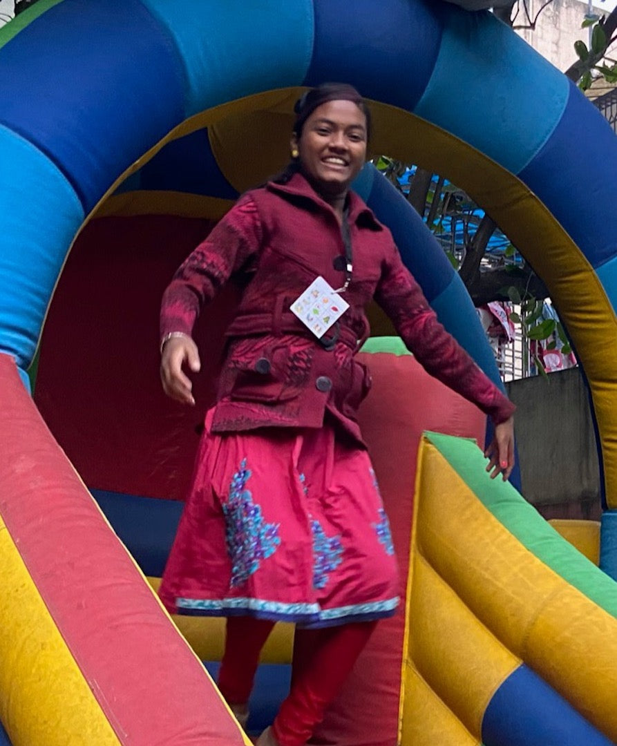 A Joyya staff member smiling and playing on a large inflatable slide. 