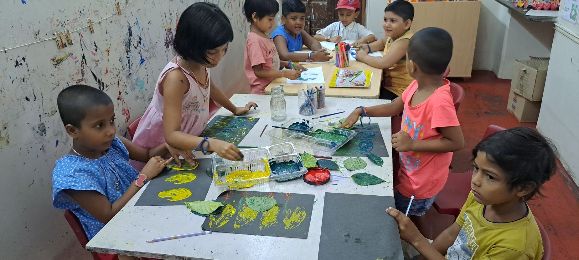 A group of children finger painting while participating in an art club. 