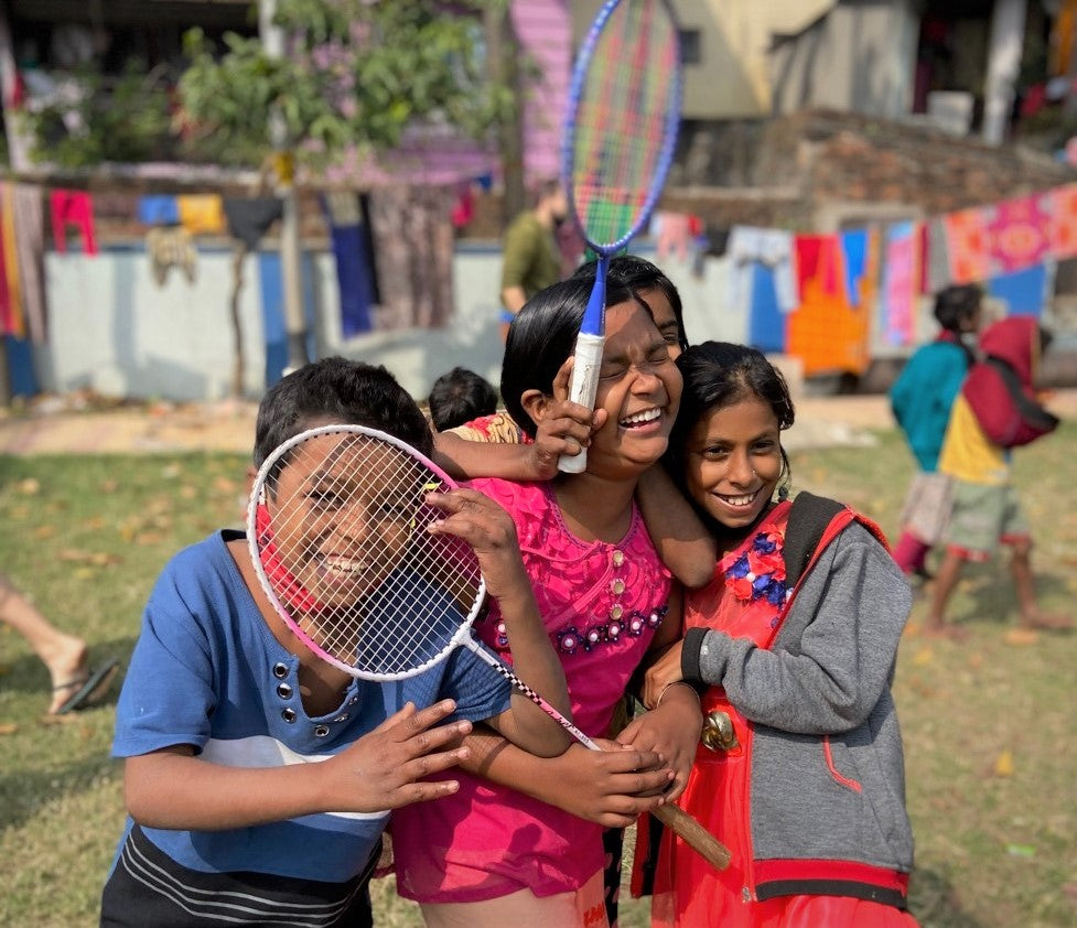 A group of children playing together with badminton rackets in their hands. 