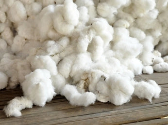 A pile of raw cotton gin piled up on a wooden table. 